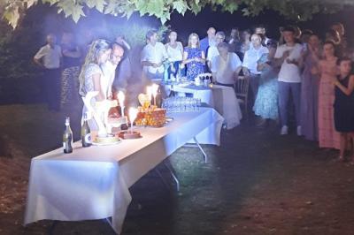 Un couple coupe un gâteau éclairé de bougies étincelantes lors d'une fête dans une salle décorée.