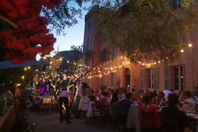 Dîner en plein air au crépuscule, avec des guirlandes lumineuses suspendues entre des arbres et des convives attablés.