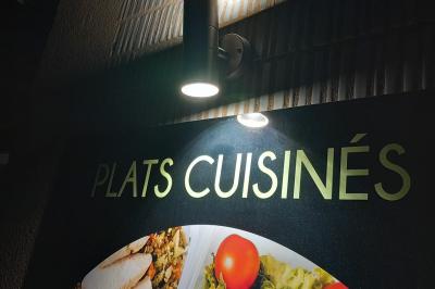 Bouteilles de vin rouge et rosé disposées sur un tonneau en bois, avec une plante en arrière-plan.