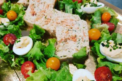 Bouteilles de vin rouge et rosé disposées sur un tonneau en bois, avec une plante en arrière-plan.