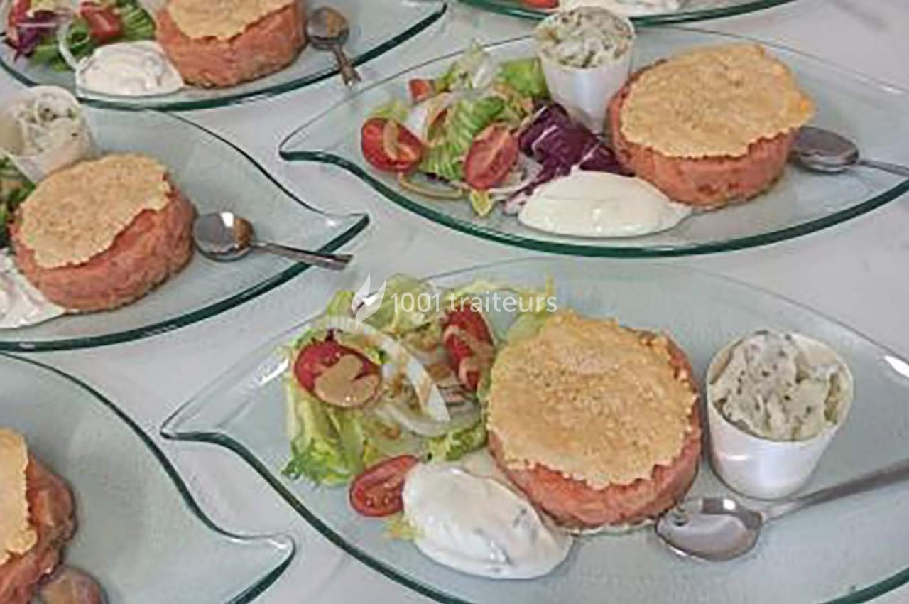 Assiettes avec tartares de saumon, salade verte, tomates cerises, sauce blanche et verrines d'accompagnement.