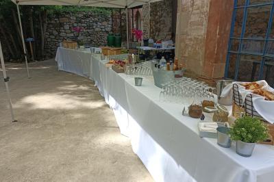 Salle en pierre aménagée pour un événement, avec tables rondes décorées et chaises blanches.