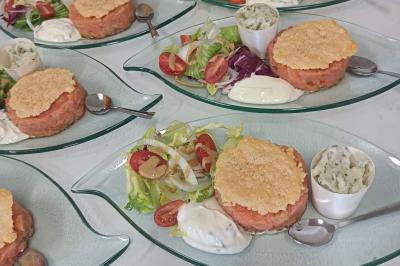 Salle en pierre aménagée pour un événement, avec tables rondes décorées et chaises blanches.