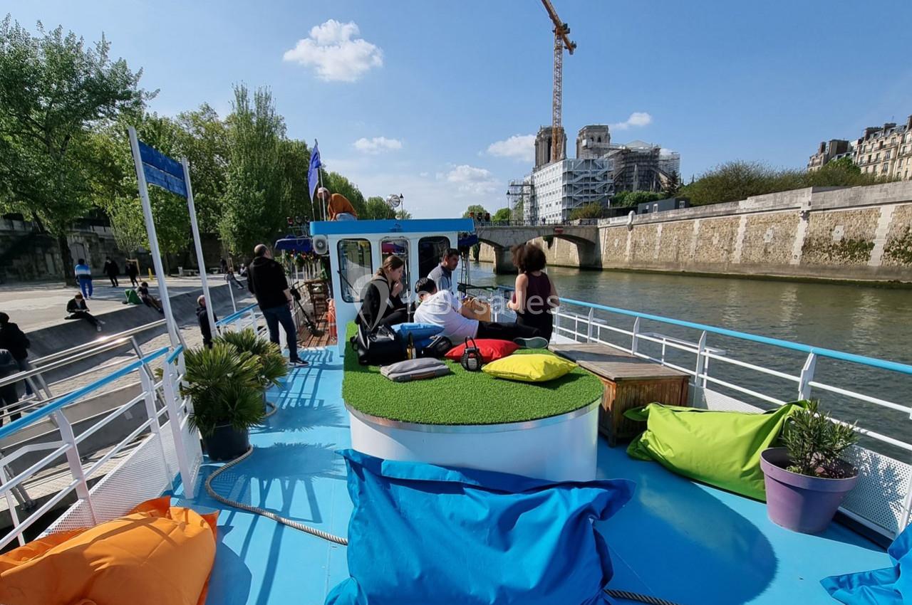 Personnes assises sur le pont d'un bateau coloré avec des coussins, naviguant sur une rivière bordée d'arbres et de…