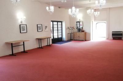 Jardin ensoleillé aménagé pour un événement avec tables hautes, tente blanche et allée décorée de fleurs.