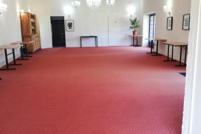 Jardin ensoleillé aménagé pour un événement avec tables hautes, tente blanche et allée décorée de fleurs.