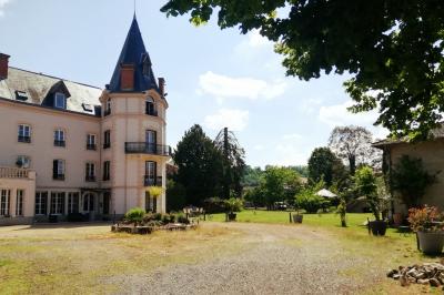 Jardin ensoleillé aménagé pour un événement avec tables hautes, tente blanche et allée décorée de fleurs.