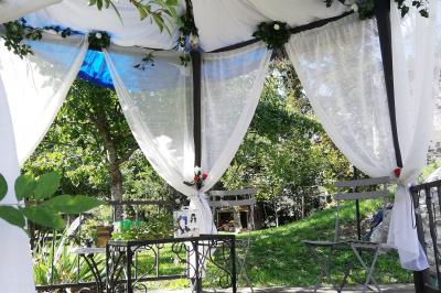 Jardin ensoleillé aménagé pour un événement avec tables hautes, tente blanche et allée décorée de fleurs.