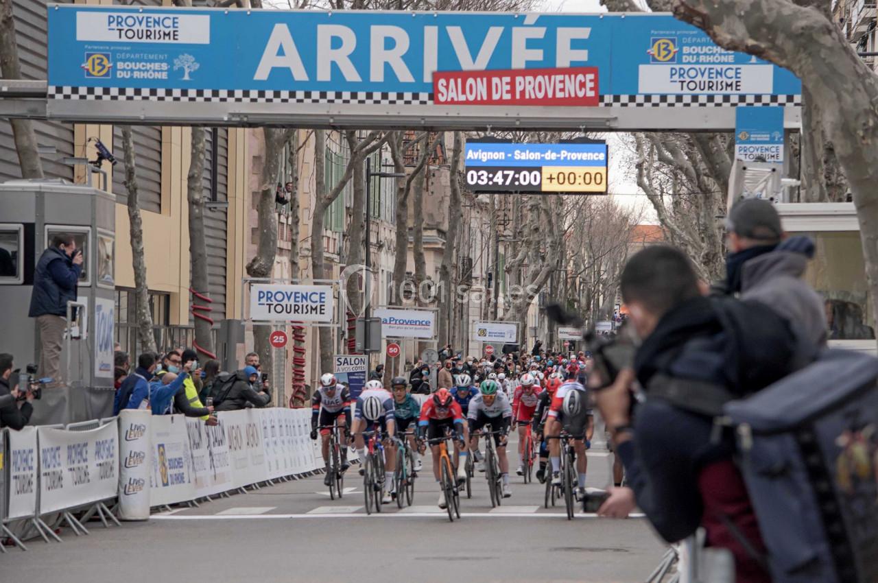 Cyclistes franchissant la ligne d'arrivée d'une course à Salon-de-Provence, sous une arche marquée ’ARRIVÉE’.