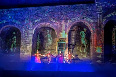 Des jeunes femmes en robes de soirée interagissent avec des résidents d'un établissement, dans une ambiance conviviale.