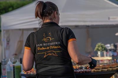 Des jeunes femmes en robes de soirée interagissent avec des résidents d'un établissement, dans une ambiance conviviale.