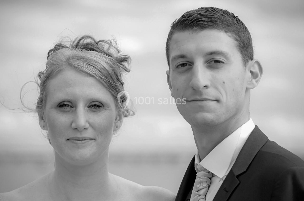 Un homme et une femme posent ensemble en extérieur, vêtus élégamment, avec un arrière-plan flou.