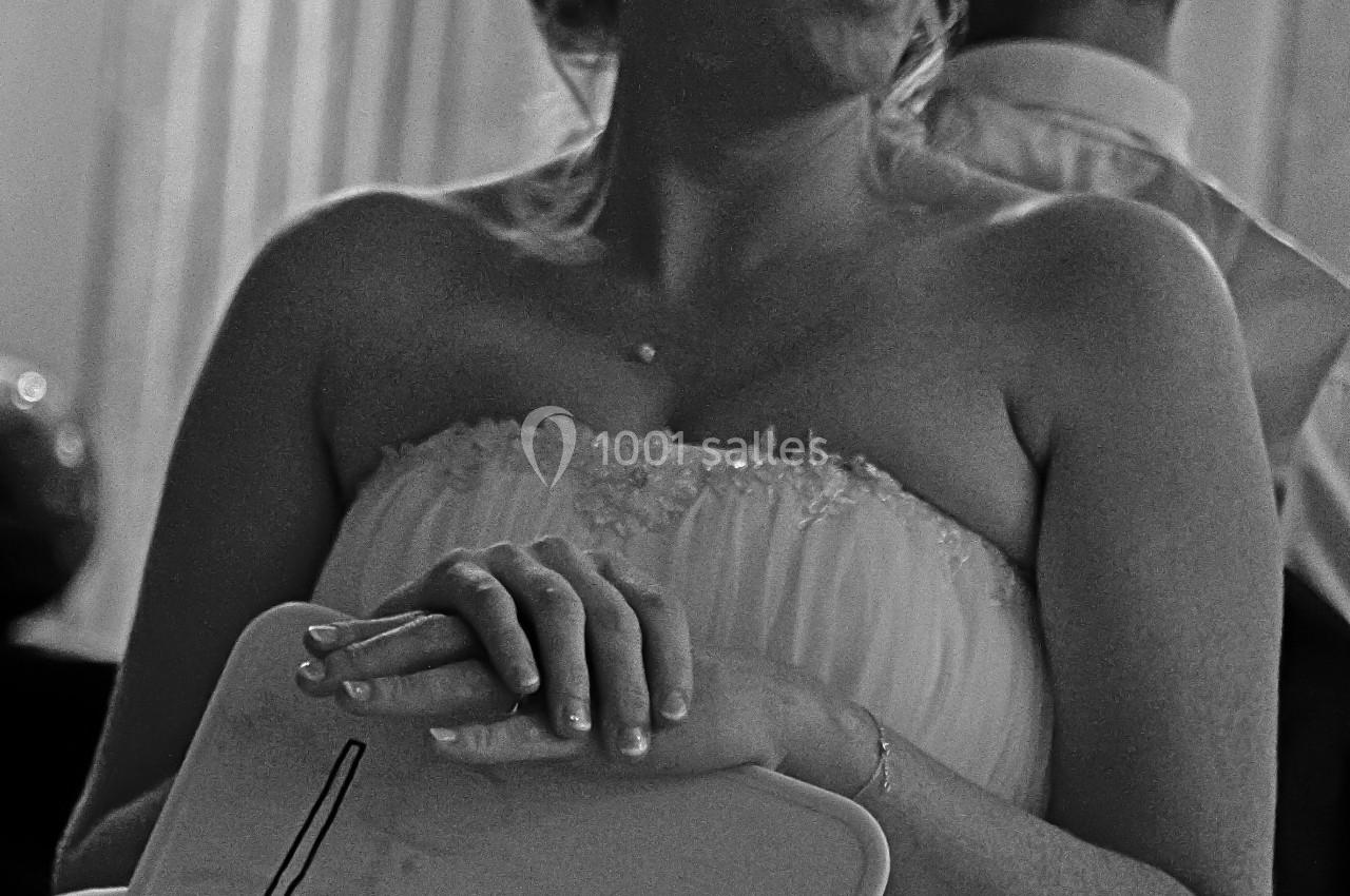 Une femme en robe de mariée tient une pancarte avec le mot ’Lui’ dans un cadre intérieur.