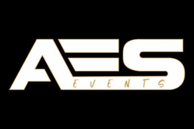 Vue depuis une table de mixage sur un groupe de personnes dansant dans une salle éclairée par une lumière rouge.