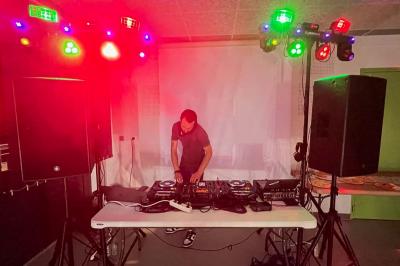 Vue depuis une table de mixage sur un groupe de personnes dansant dans une salle éclairée par une lumière rouge.