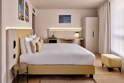 Miniature Chambre standard Façade d'un hôtel moderne avec enseigne lumineuse ’Crowne Plaza’ au crépuscule, entourée de végétation et d'immeubles.