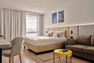 Miniature Chambre standard Façade d'un hôtel moderne avec enseigne lumineuse ’Crowne Plaza’ au crépuscule, entourée de végétation et d'immeubles.