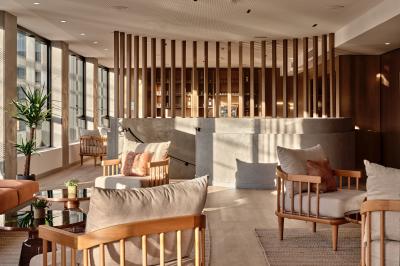 Miniature Espace Bar Lounge Façade d'un hôtel moderne avec enseigne lumineuse ’Crowne Plaza’ au crépuscule, entourée de végétation et d'immeubles.