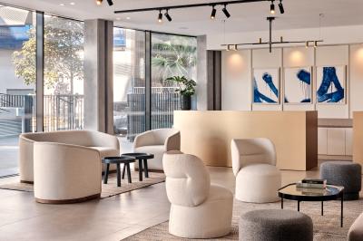 Miniature Lobby Façade d'un hôtel moderne avec enseigne lumineuse ’Crowne Plaza’ au crépuscule, entourée de végétation et d'immeubles.