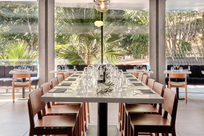 Miniature Restaurant Façade d'un hôtel moderne avec enseigne lumineuse ’Crowne Plaza’ au crépuscule, entourée de végétation et d'immeubles.