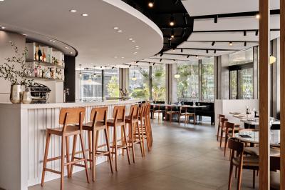 Miniature Restaurant Façade d'un hôtel moderne avec enseigne lumineuse ’Crowne Plaza’ au crépuscule, entourée de végétation et d'immeubles.