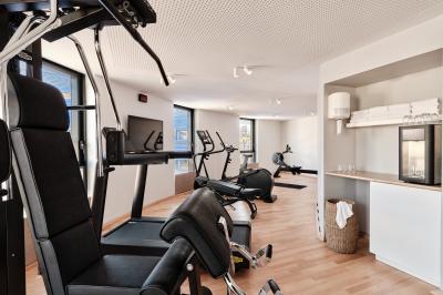 Miniature Salle de sport Façade d'un hôtel moderne avec enseigne lumineuse ’Crowne Plaza’ au crépuscule, entourée de végétation et d'immeubles.