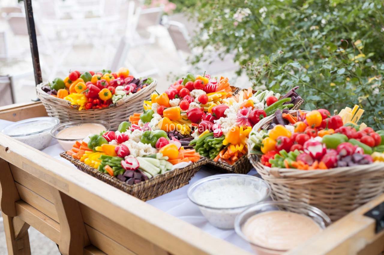 Plateau de légumes frais colorés présentés dans des paniers en osier, accompagnés de sauces en bols.