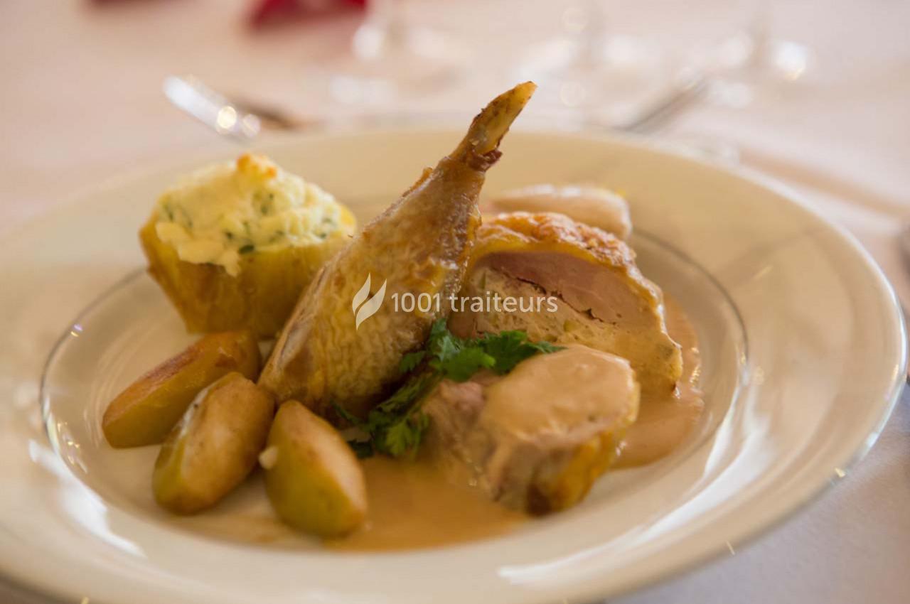 Assiette de caille rôtie accompagnée de pommes de terre, purée et sauce, servie sur une table dressée.