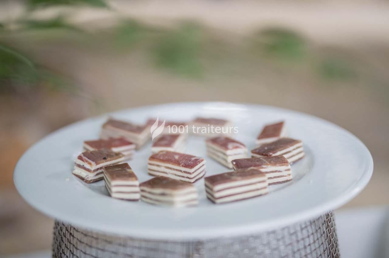 Assortiment de petits gâteaux en couches sur une assiette blanche, posée sur un support métallique.