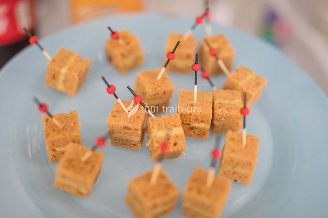 Carrés de gâteau surmontés de cure-dents rouges et noirs, disposés sur une assiette bleue.