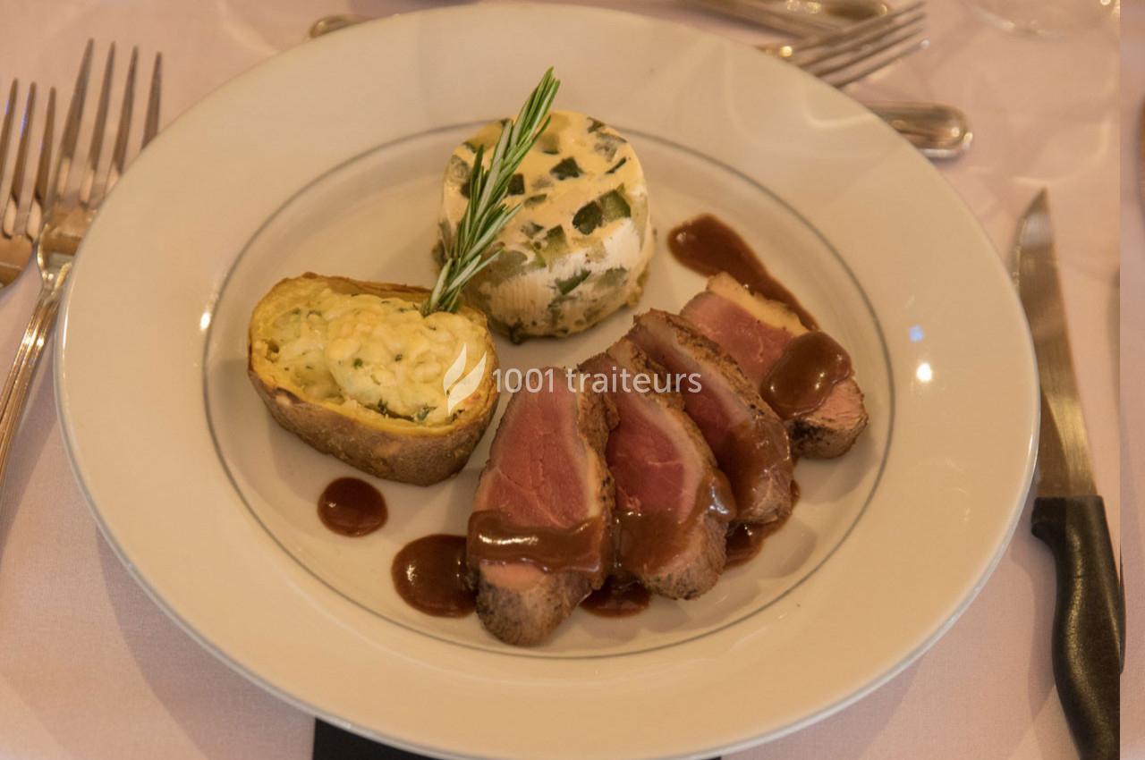 Assiette contenant des tranches de viande sauce brune, une pomme de terre farcie et un flan aux herbes.
