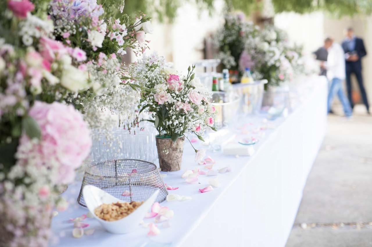 Table décorée avec des fleurs, pétales et snacks, disposée pour un événement en extérieur.