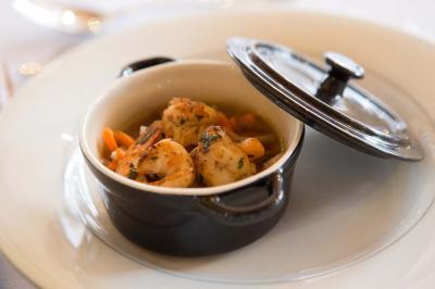 Assiette contenant une mousse verte garnie de persil, accompagnée de tomates rôties et de points de sauce balsamique.