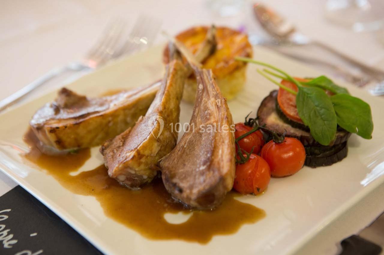 Assiette de côtelettes d'agneau avec sauce, légumes grillés, tomates cerises et garniture de pommes de terre.