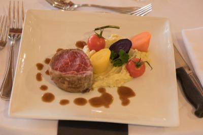 Assiette contenant une mousse verte garnie de persil, accompagnée de tomates rôties et de points de sauce balsamique.