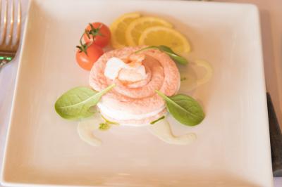 Assiette contenant une mousse verte garnie de persil, accompagnée de tomates rôties et de points de sauce balsamique.