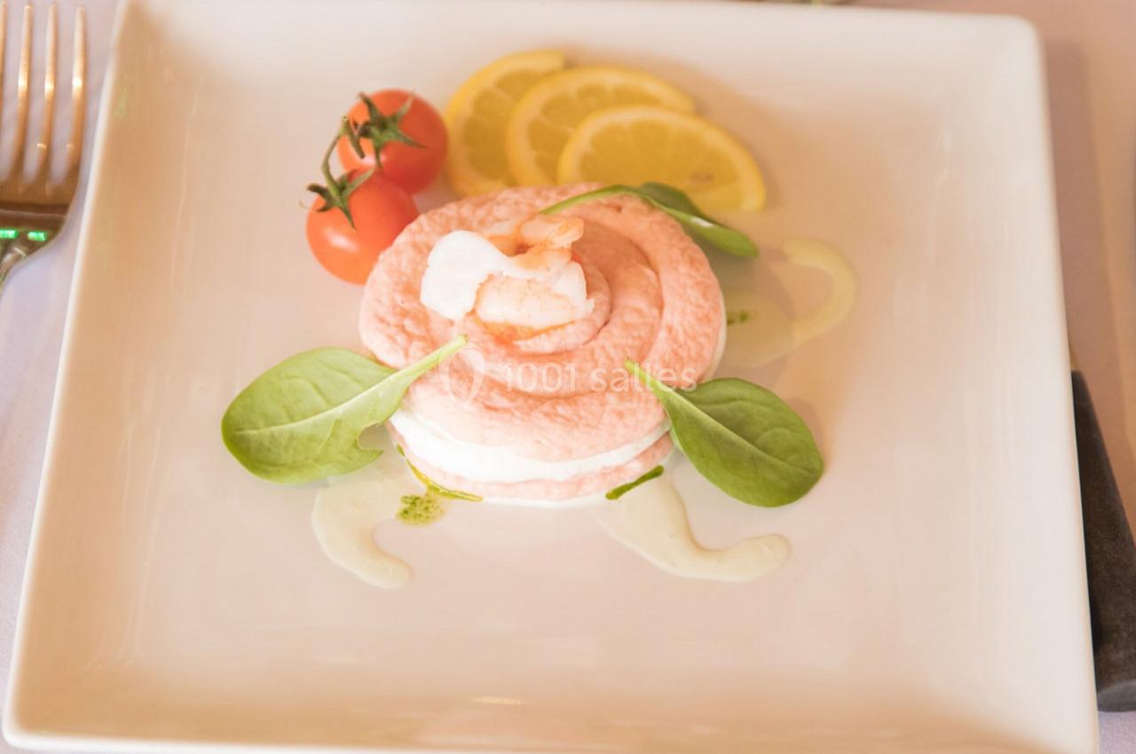 Entrée élégante composée de mousse rose, crevette, feuilles de salade, tomates cerises et tranches de citron.