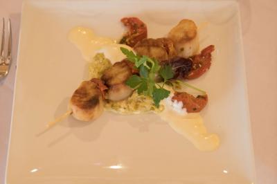 Assiette contenant une mousse verte garnie de persil, accompagnée de tomates rôties et de points de sauce balsamique.