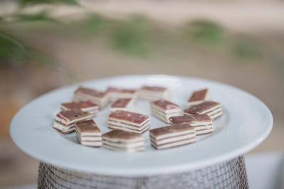 Assortiment de petits gâteaux en couches sur une assiette blanche, posée sur un support métallique.