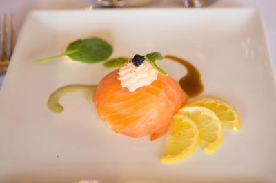 Assiette contenant une mousse verte garnie de persil, accompagnée de tomates rôties et de points de sauce balsamique.