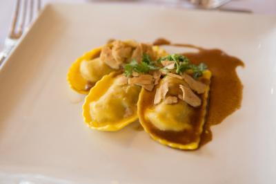 Assiette contenant une mousse verte garnie de persil, accompagnée de tomates rôties et de points de sauce balsamique.