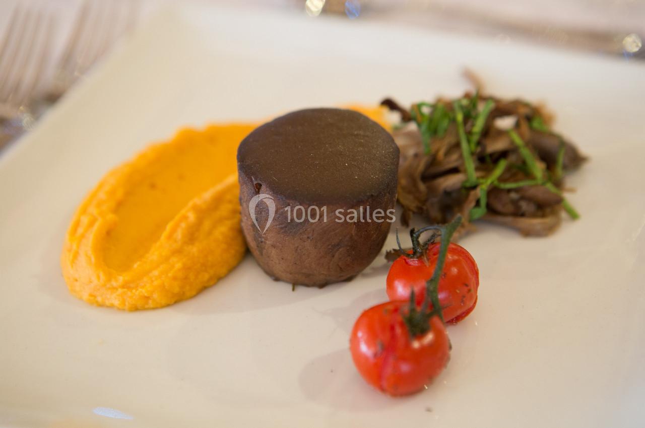 Assiette gastronomique avec purée orange, pièce de viande, champignons sautés et tomates cerises grillées.