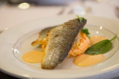Assiette contenant une mousse verte garnie de persil, accompagnée de tomates rôties et de points de sauce balsamique.