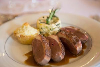Assiette contenant une mousse verte garnie de persil, accompagnée de tomates rôties et de points de sauce balsamique.