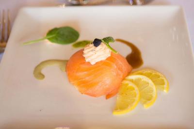 Assiette contenant une mousse verte garnie de persil, accompagnée de tomates rôties et de points de sauce balsamique.