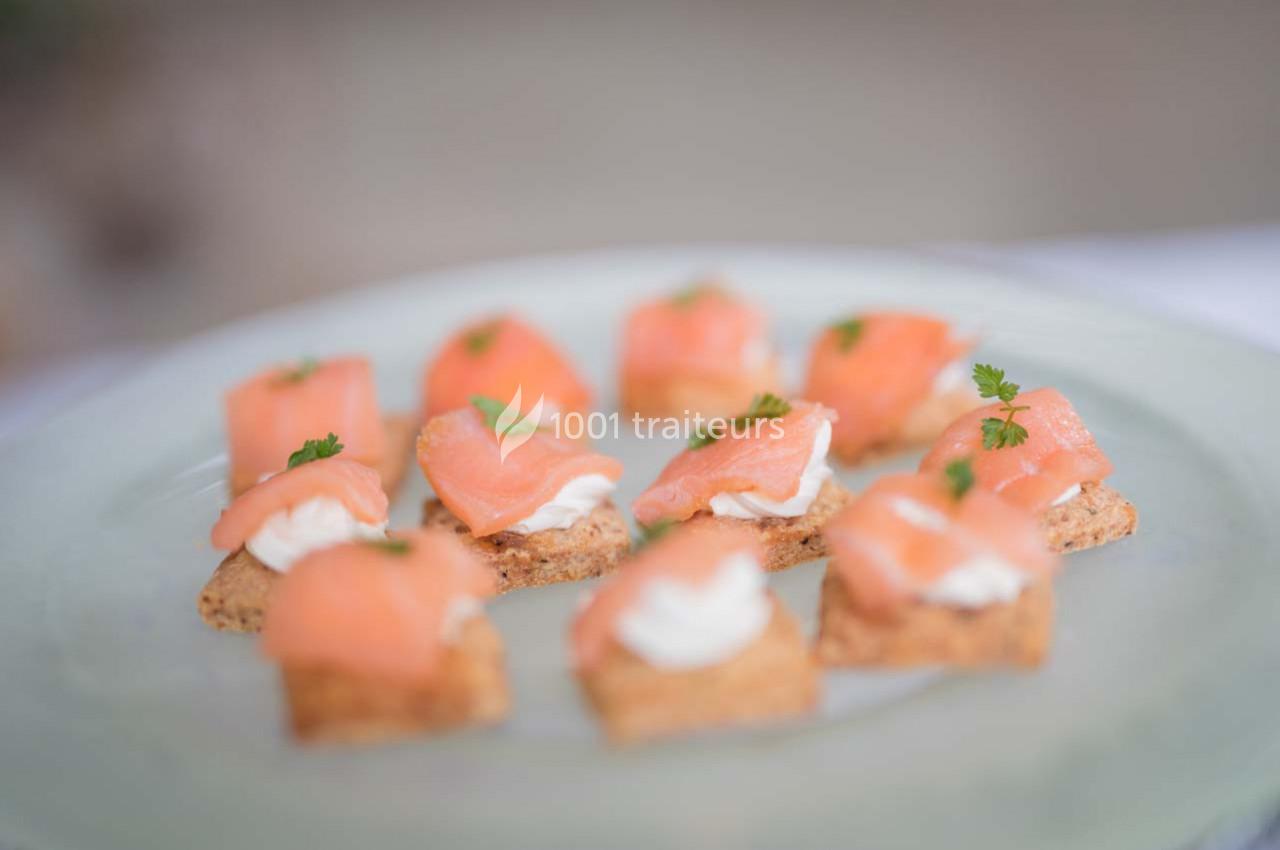 Assortiment de canapés au saumon fumé, crème et herbes fraîches, disposés sur une assiette claire.