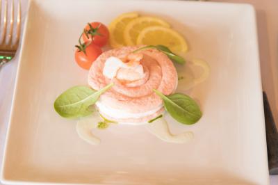Assiette contenant une mousse verte garnie de persil, accompagnée de tomates rôties et de points de sauce balsamique.