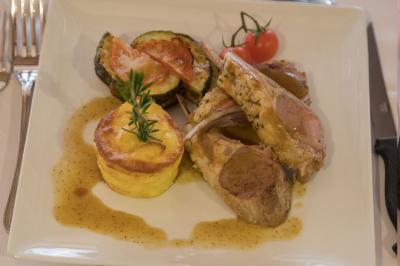 Assiette contenant une mousse verte garnie de persil, accompagnée de tomates rôties et de points de sauce balsamique.