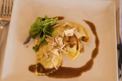 Assiette contenant une mousse verte garnie de persil, accompagnée de tomates rôties et de points de sauce balsamique.