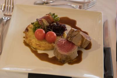 Assiette contenant une mousse verte garnie de persil, accompagnée de tomates rôties et de points de sauce balsamique.